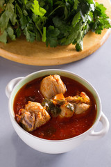Chakhokhbili with chicken legs, parsley and tomatoes on a gray background. Chicken in tomato sauce.