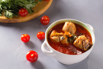 Chakhokhbili with chicken legs, parsley and tomatoes on a gray background. Chicken in tomato sauce.