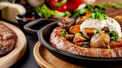 Turkish oriental cuisine. Homemade sausage, with fried mushrooms, green onions, and kaimak sauce. Serving dishes in restaurant in a cast-iron pan. background image, copy space text