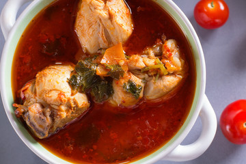 Chakhokhbili with chicken legs, parsley and tomatoes on a gray background. Chicken in tomato sauce.