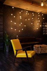 Modern interior in a dark color with a leather sofa, leather chair and lights. Loft style living room