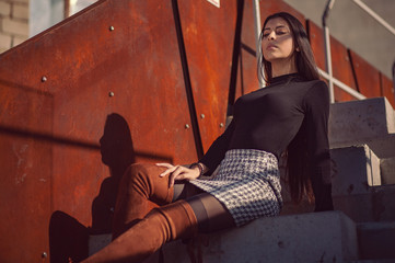 stylish girl model posing sitting on the steps of the building