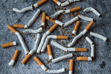 A pile of broken cigarettes on a gray textural background. The concept of a healthy lifestyle, quitting Smoking