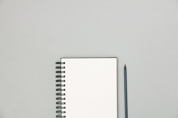 Blank notepad with pencil for notes on gray background, top view. Plans and goals for the year. Freelancer workplace concept. 