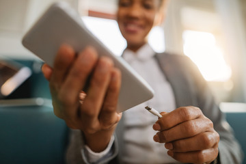 Close-up of African American businesswoman charging her mobile phone. - obrazy, fototapety, plakaty