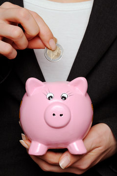 Savings Image of a business woman putting a Euro coin into a piggy bank