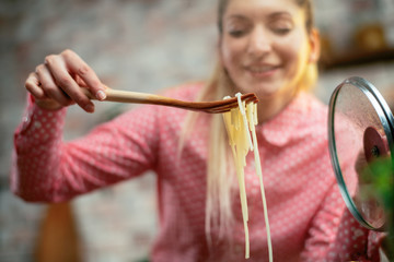 Close up of woman eating spaghetti. Beautiful woman cooking pasta. Young woman in kitchen. 