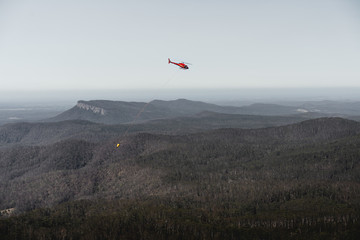 Mount Comboyne - December 30th 2019: A helicopter drops water on a spot fire as seen from the top of Mount Comboyne.