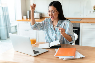 Woman using laptop computer holding credit card.