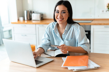 Woman using laptop computer holding credit card.