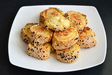 Delicious snack of French (puff) pastry rolled with ham and cheese and sprinkled with sesame seeds