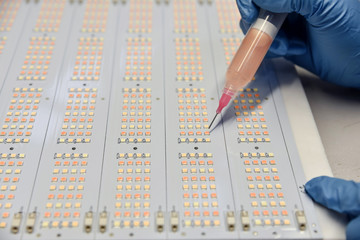 Women in insulated gloves apply  the luminophore on SMD LED using injector and syringe