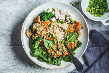 Lentil vegan stew with mushrooms, quinoa, spinach and broccoli in a bowl, top view. Healthy vegan food concept.