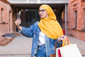 Sale, technologies and buying concept - Happy arab muslim woman taking selfie outdoors after...