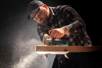 Carpenter slashes the board using an electric saw.