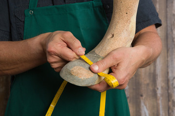 close up of orthopedic shoemaker hands checking quality of a wooden last 