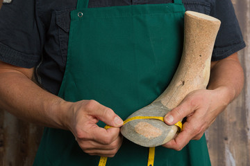 close up of orthopedic shoemaker hands checking quality of a wooden last 