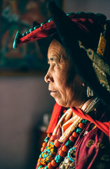 Portrait of a woman in traditional tibetan clothes inside her house in Ladakh, Kashmir, India - 325676665