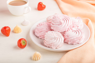 Pink strawberry homemade zephyr or marshmallow with cup of coffee on white wooden background. side view, selective focus.