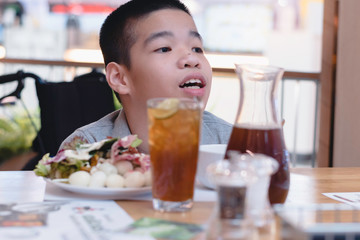 Disabled child on wheelchair with food and water on table in public restaurant, Special children's lifestyle, Life in the education age of special need child, Happy disability kid concept.