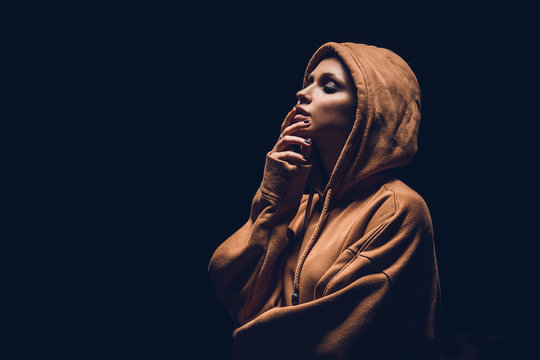 Studio Portrait Of A Girl In A Hoodie On A Dark Background