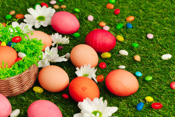 Close up photo of colored Easter eggs and candies on grass