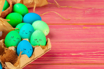 Blue and green colored Easter eggs with drawn funny faces. Creative photo