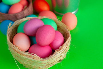 Fototapeta na wymiar Vibrant colored eggs in a nest on green. Easter concept