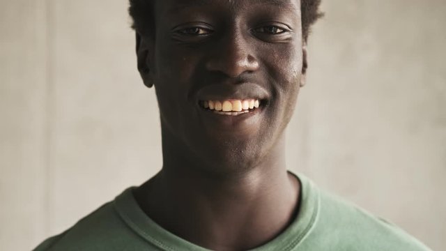 A close-up view of a positive laughing handsome young african american man is turning to the camera in the light living room