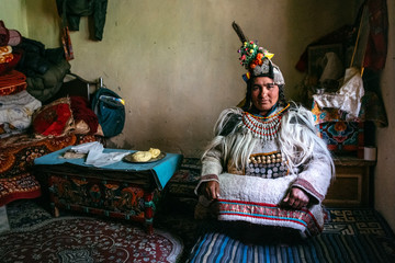 Portrait of a woman in typical tibetan clothes inside her house in Ladakh, Kashmir, India.