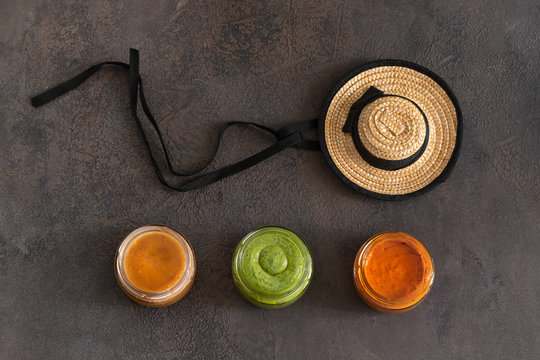 Three famous Canary islands sauces Mojo picon ,Red hot sauce, and  Mojo verde , Green sauce and Almogrote, cheese  and typical Canarias hat on concrete background. Top view