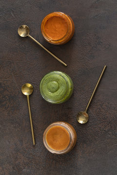 Three famous Canary islands sauces Mojo picon ,Red hot sauce, and  Mojo verde , Green sauce and Almogrote, cheese   on concrete background. Top view