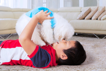 Obraz premium Boy rubbing nose with his white dog in his home