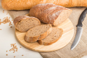 Sliced bread with different kinds of fresh baked bread on a white wooden background. side view, selective focus.