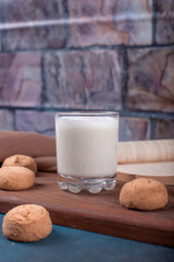 Butter cookies and a glass of milk on a wooden cutting board on the table