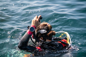 An Asian scuba diving girl with back wet suit waring dive computer at wrist
