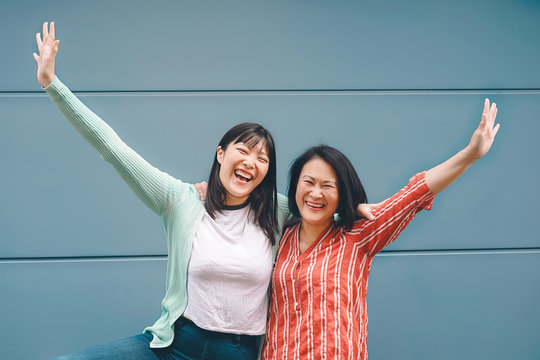 Happy Asian family having fun  outdoor - Chinese mother and daughter enjoying time together outside - Parents lifestyle relationship and youth and older people concept - Blue background
