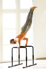 Man doing handstand push ups on bars