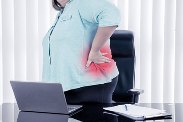 Fat businesswoman rubbing her waist while working