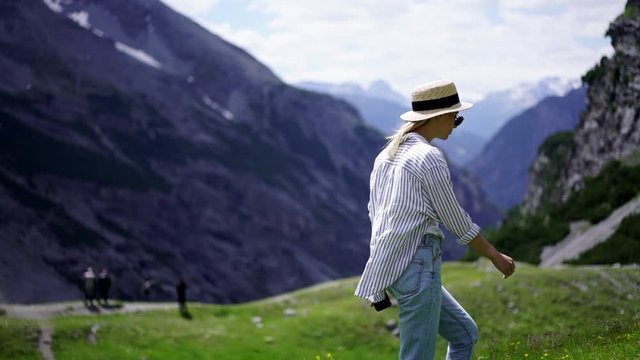 Slow motion effect of woman traveler wanderlust walking on pathway in mountains exploring nature, female tourist enjoying vacation and hiking tour in Italian alps in summer