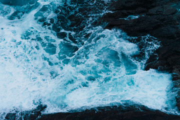 White sea foam produced when the waves collide with the rocks of the coast