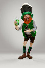 Excited leprechaun in green suit with red beard enjoying green beer pint on white background. Funny...