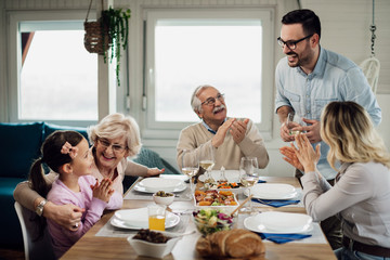 Happy extended family having fun while celebrating during lunch at dining table.