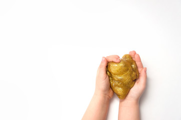 Kids hands stretching and playing golden glitter slime toy on white background. Isolated. Making slime.