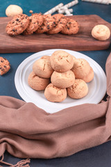 Butter biscuits in a white platter and oatmeal cookies on a woode board