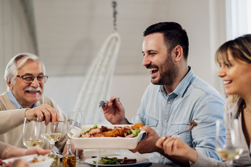 Cheerful man having fun during family lunch at home.