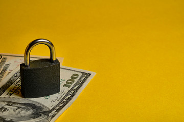 dollar banknotes and metal padlock at yellow background. Safety shopping, personal finances...