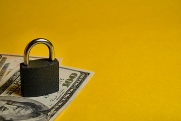 dollar banknotes and metal padlock at yellow background. Safety shopping, personal finances security, money savings