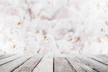 Empty wood table top and blurred sakura flower tree in garden background with vintage filter - can used for display or montage your products. © bunditinay