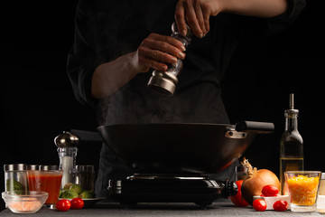 Cooking dishes with meat and vegetables in a wok. Pepper a dish. Freezing in motion. Oriental cuisine, Asia food. Seasoning, freezing in movement. Vegetables and meat, tasty and healthy food.